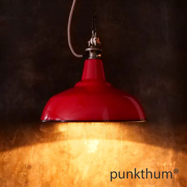 Rote Emaillelampe, Industrielampe mit Stahlguss-Aufhängung und Textilkabel, eingeschaltet.