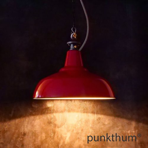 Rote Emaillelampe, Industrielampe mit Stahlguss-Aufhängung und Textilkabel, eingeschaltet.