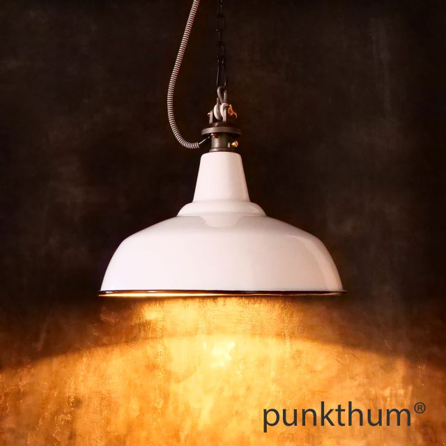 Weisse Emaillelampe, Industrielampe mit Stahlguss-Aufhängung und Textilkabel, eingeschaltet.