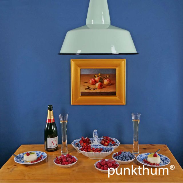 Große apfelgrüne Emaillelampe über dem Tisch.